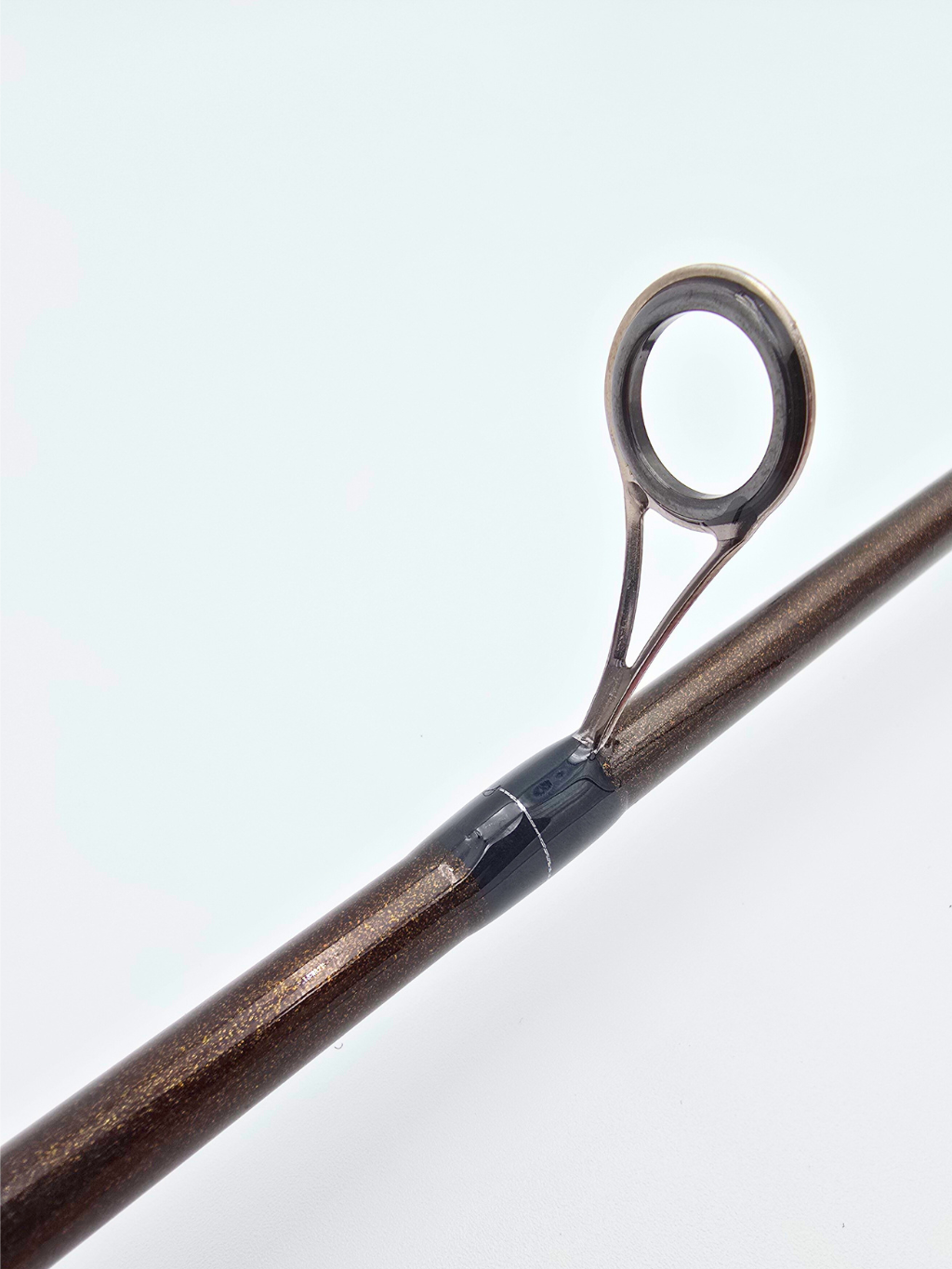 Vue rapprochée d’un guide en acier inoxydable monté sur une canne Alpha Carbon, finition brun métallisé avec ligature noire.