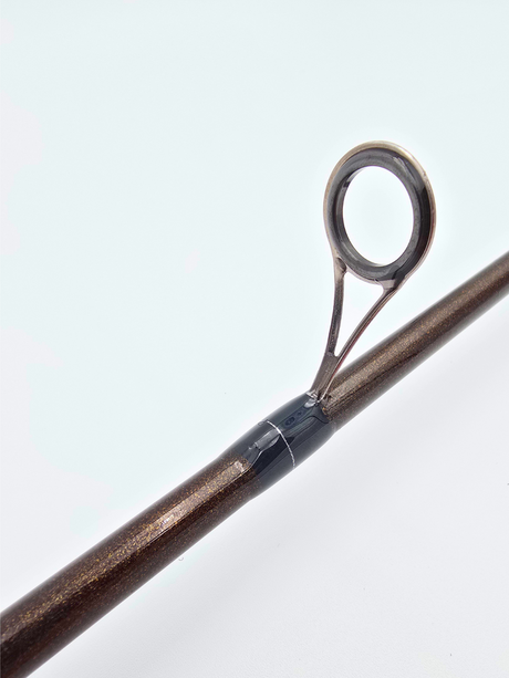 Vue rapprochée d’un guide en acier inoxydable monté sur une canne Alpha Carbon, finition brun métallisé avec ligature noire.